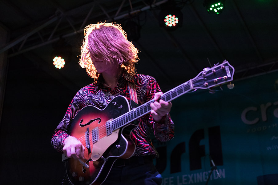 Guitarist performing on stage at Crave under colorful lights.