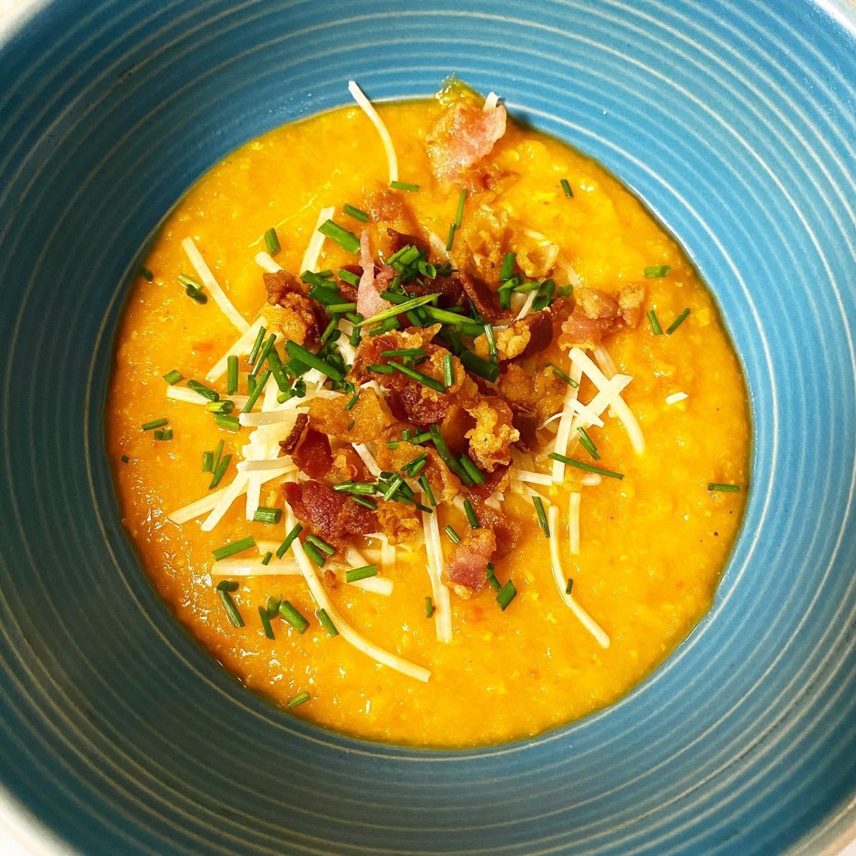 A bowl of creamy grits topped with bacon, parmesan, and chives from Daughter's Southern.