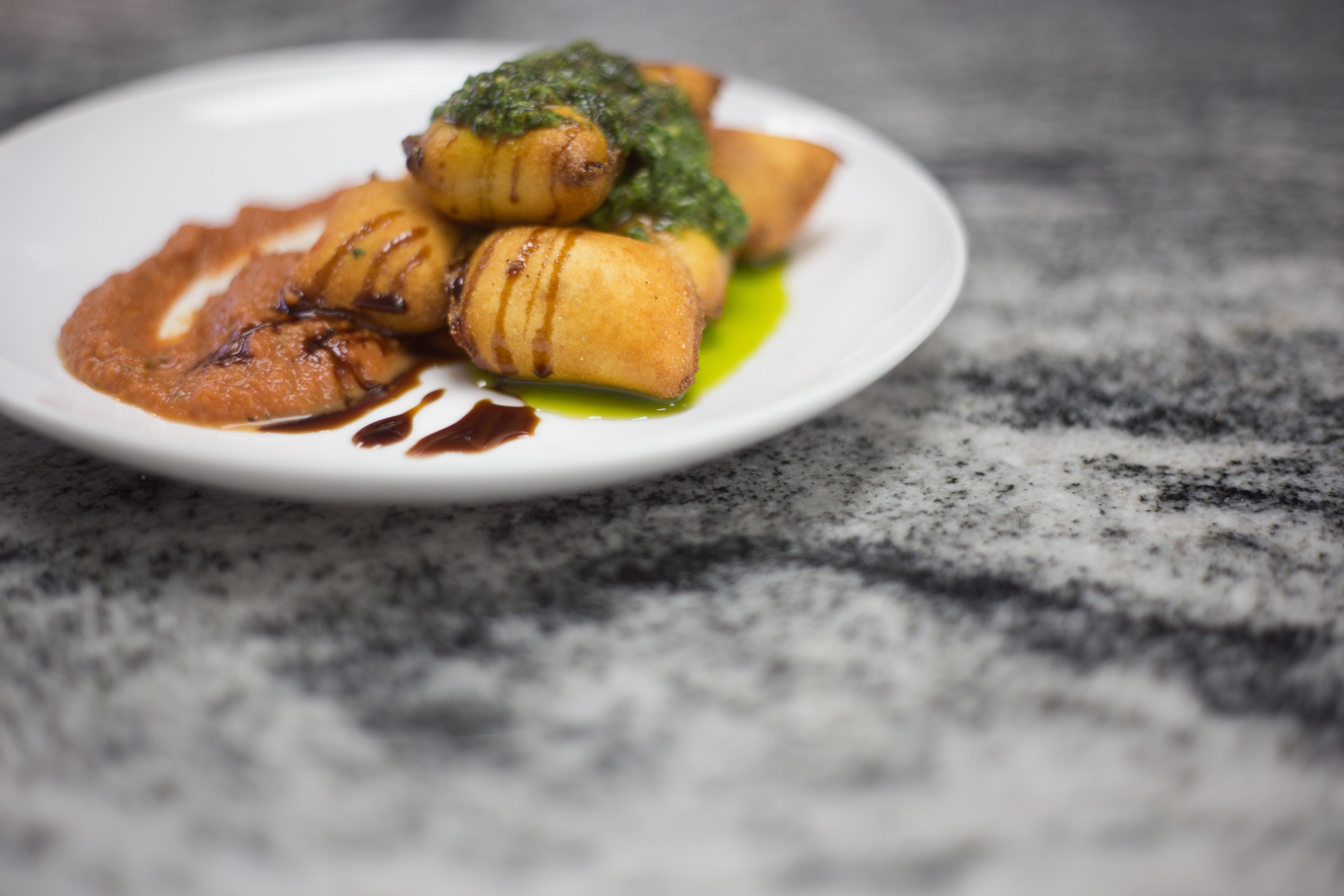 Plated stuffed pasta with pesto and tomato sauce from Pasta Garage Italian Cafe.